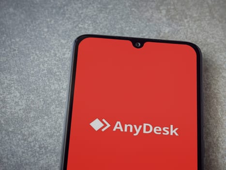 Lod, Israel - July 16,2023: Anydesk app launch screen on smartphone on ceramic stone background. Top view flat lay with copy space.