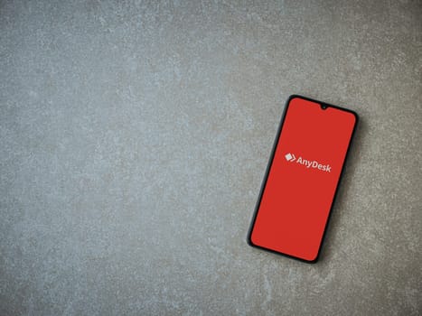 Lod, Israel - July 16,2023: Anydesk app launch screen on smartphone on ceramic stone background. Top view flat lay with copy space.