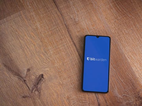 Lod, Israel - July 16,2023: Bitwarden Password Manager app launch screen on smartphone on wooden background. Top view flat lay with copy space.