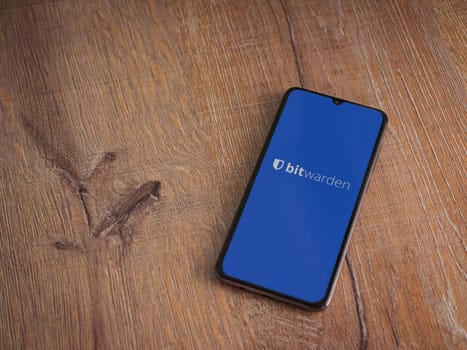 Lod, Israel - July 16,2023: Bitwarden Password Manager app launch screen on smartphone on wooden background. Top view flat lay with copy space.