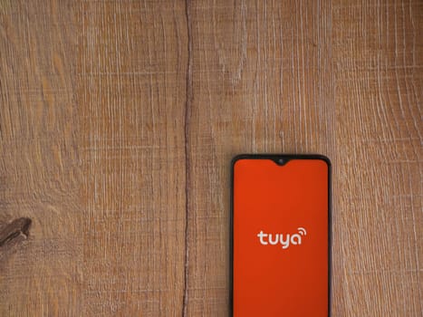 Lod, Israel - July 16,2023: Tuya Smart app launch screen on smartphone on wooden background. Top view flat lay with copy space.