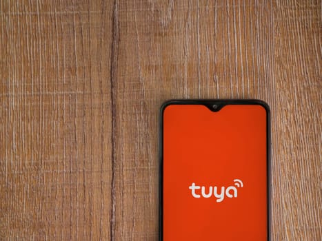 Lod, Israel - July 16,2023: Tuya Smart app launch screen on smartphone on wooden background. Top view flat lay with copy space.