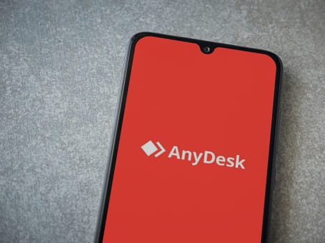 Lod, Israel - July 16,2023: Anydesk app launch screen on smartphone on ceramic stone background. Top view flat lay with copy space.