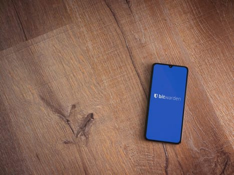 Lod, Israel - July 16,2023: Bitwarden Password Manager app launch screen on smartphone on wooden background. Top view flat lay with copy space.