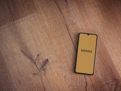 Lod, Israel - July 16,2023: Sonos app launch screen on smartphone on wooden background. Top view flat lay with copy space.