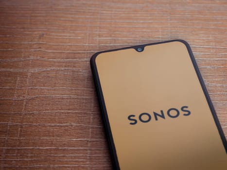Lod, Israel - July 16,2023: Sonos app launch screen on smartphone on wooden background. Top view flat lay with copy space.