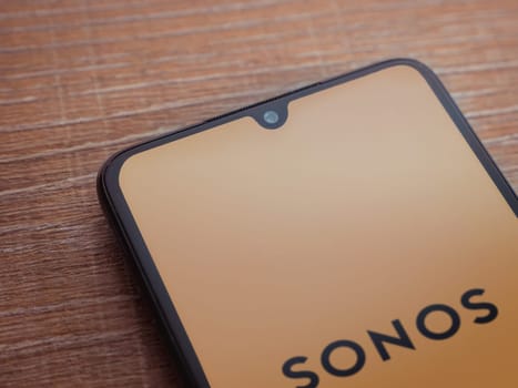 Lod, Israel - July 16,2023: Sonos app launch screen on smartphone on wooden background. Top view flat lay with copy space.