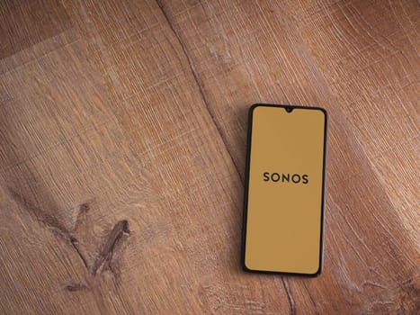 Lod, Israel - July 16,2023: Sonos app launch screen on smartphone on wooden background. Top view flat lay with copy space.