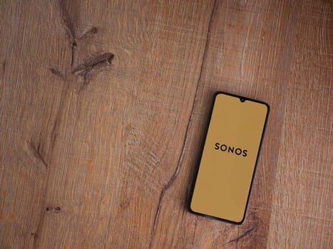 Lod, Israel - July 16,2023: Sonos app launch screen on smartphone on wooden background. Top view flat lay with copy space.