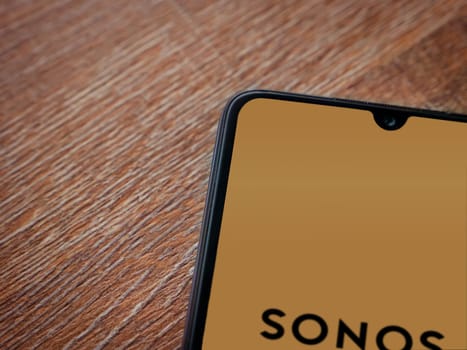 Lod, Israel - July 16,2023: Sonos app launch screen on smartphone on wooden background. Top view flat lay with copy space.