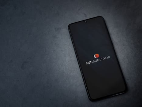 Lod, Israel - July 16,2023: Sun Surveyor app launch screen on smartphone on dark marble stone background. Top view flat lay with copy space.