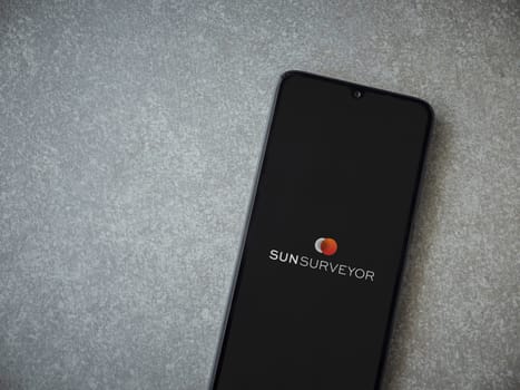 Lod, Israel - July 16,2023: Sun Surveyor app launch screen on smartphone on ceramic stone background. Top view flat lay with copy space.