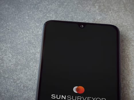 Lod, Israel - July 16,2023: Sun Surveyor app launch screen on smartphone on ceramic stone background. Top view flat lay with copy space.