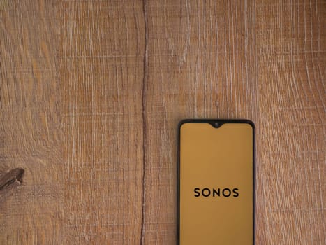 Lod, Israel - July 16,2023: Sonos app launch screen on smartphone on wooden background. Top view flat lay with copy space.