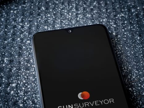 Lod, Israel - July 16,2023: Sun Surveyor app launch screen on smartphone on metallic background. Close up top view flat lay.