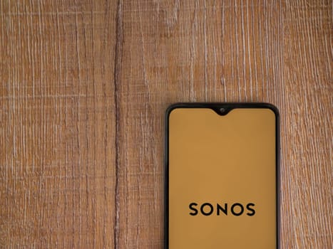 Lod, Israel - July 16,2023: Sonos app launch screen on smartphone on wooden background. Top view flat lay with copy space.