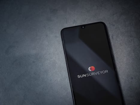 Lod, Israel - July 16,2023: Sun Surveyor app launch screen on smartphone on dark marble stone background. Top view flat lay with copy space.