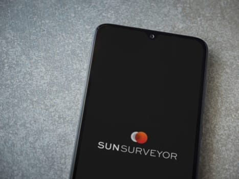Lod, Israel - July 16,2023: Sun Surveyor app launch screen on smartphone on ceramic stone background. Top view flat lay with copy space.