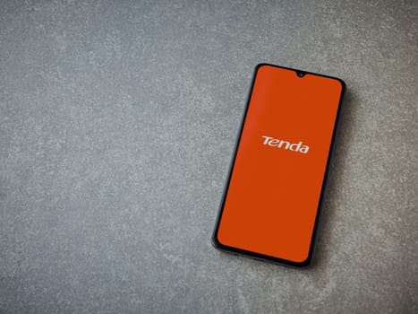 Lod, Israel - July 16,2023: Tenda Wifi app launch screen on smartphone on ceramic stone background. Top view flat lay with copy space.
