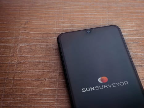 Lod, Israel - July 16,2023: Sun Surveyor app launch screen on smartphone on wooden background. Top view flat lay with copy space.