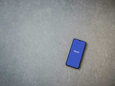 Lod, Israel - July 16,2023: Wear - Galaxy Wearable app launch screen on smartphone on ceramic stone background. Top view flat lay with copy space.