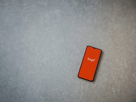 Lod, Israel - July 16,2023: Tuya Smart app launch screen on smartphone on ceramic stone background. Top view flat lay with copy space.