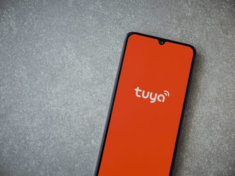 Lod, Israel - July 16,2023: Tuya Smart app launch screen on smartphone on ceramic stone background. Top view flat lay with copy space.