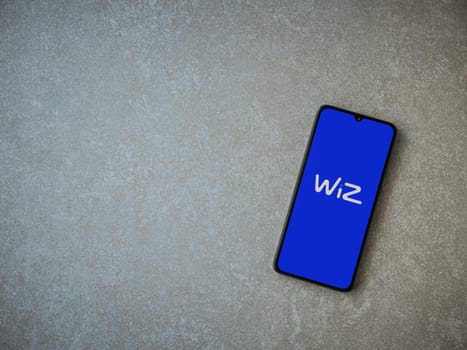 Lod, Israel - July 16,2023: WIZ app launch screen on smartphone on ceramic stone background. Top view flat lay with copy space.