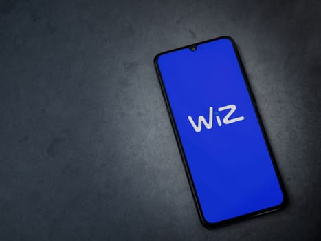 Lod, Israel - July 16,2023: WIZ app launch screen on smartphone on dark marble stone background. Top view flat lay with copy space.