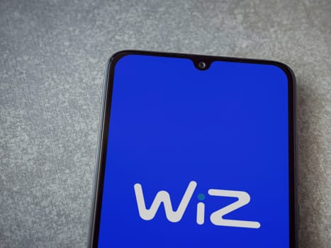 Lod, Israel - July 16,2023: WIZ app launch screen on smartphone on ceramic stone background. Top view flat lay with copy space.
