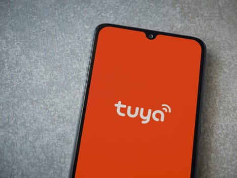Lod, Israel - July 16,2023: Tuya Smart app launch screen on smartphone on ceramic stone background. Top view flat lay with copy space.