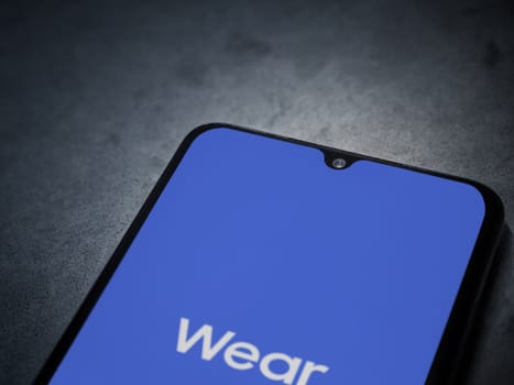 Lod, Israel - July 16,2023: Wear - Galaxy Wearable app launch screen on smartphone on dark marble stone background. Top view flat lay with copy space.