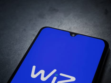 Lod, Israel - July 16,2023: WIZ app launch screen on smartphone on dark marble stone background. Top view flat lay with copy space.