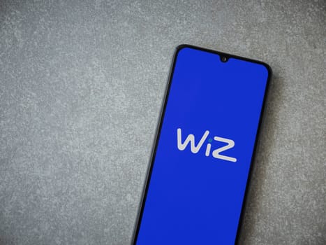 Lod, Israel - July 16,2023: WIZ app launch screen on smartphone on ceramic stone background. Top view flat lay with copy space.