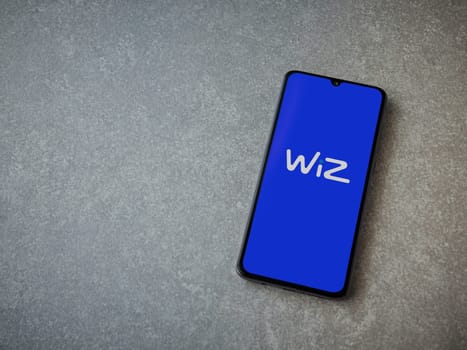 Lod, Israel - July 16,2023: WIZ app launch screen on smartphone on ceramic stone background. Top view flat lay with copy space.