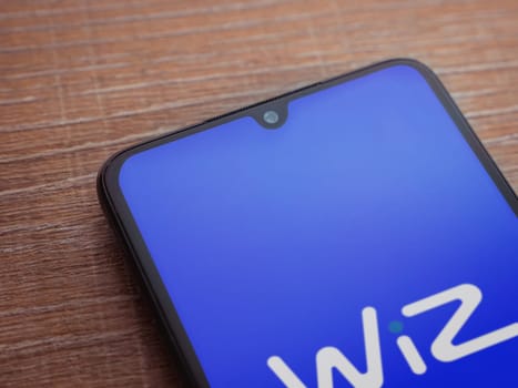 Lod, Israel - July 16,2023: WIZ app launch screen on smartphone on wooden background. Top view flat lay with copy space.