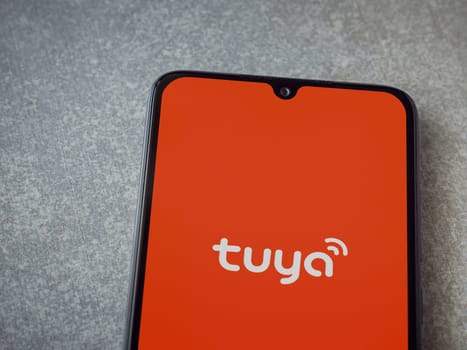 Lod, Israel - July 16,2023: Tuya Smart app launch screen on smartphone on ceramic stone background. Top view flat lay with copy space.