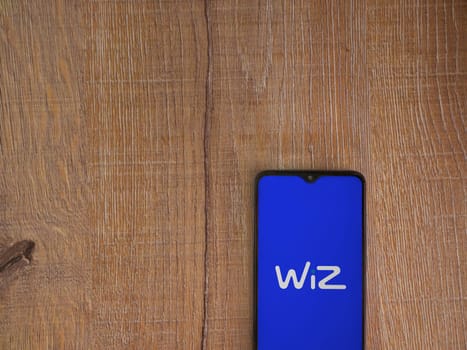 Lod, Israel - July 16,2023: WIZ app launch screen on smartphone on wooden background. Top view flat lay with copy space.