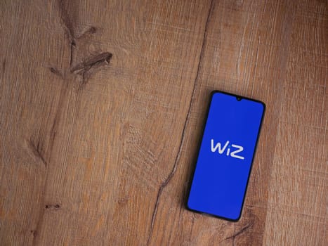 Lod, Israel - July 16,2023: WIZ app launch screen on smartphone on wooden background. Top view flat lay with copy space.