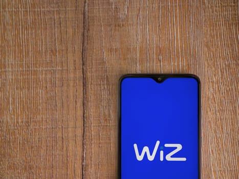 Lod, Israel - July 16,2023: WIZ app launch screen on smartphone on wooden background. Top view flat lay with copy space.