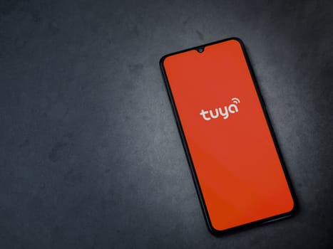Lod, Israel - July 16,2023: Tuya Smart app launch screen on smartphone on dark marble stone background. Top view flat lay with copy space.