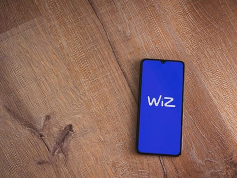 Lod, Israel - July 16,2023: WIZ app launch screen on smartphone on wooden background. Top view flat lay with copy space.