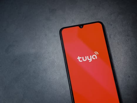 Lod, Israel - July 16,2023: Tuya Smart app launch screen on smartphone on dark marble stone background. Top view flat lay with copy space.