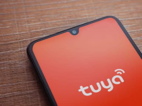 Lod, Israel - July 16,2023: Tuya Smart app launch screen on smartphone on wooden background. Top view flat lay with copy space.