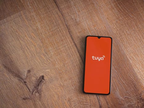Lod, Israel - July 16,2023: Tuya Smart app launch screen on smartphone on wooden background. Top view flat lay with copy space.
