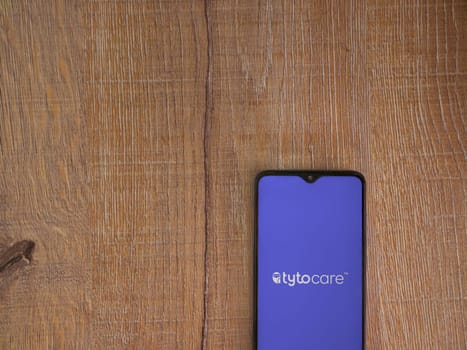 Lod, Israel - July 16,2023: TytoCare app launch screen on smartphone on wooden background. Top view flat lay with copy space.