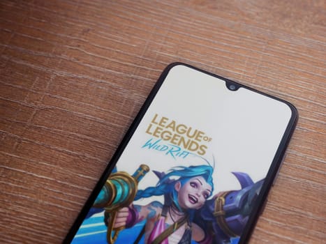 Lod, Israel - July 16,2023: League of Legends - Wild Rift app launch screen on smartphone on wooden background. Top view flat lay with copy space.