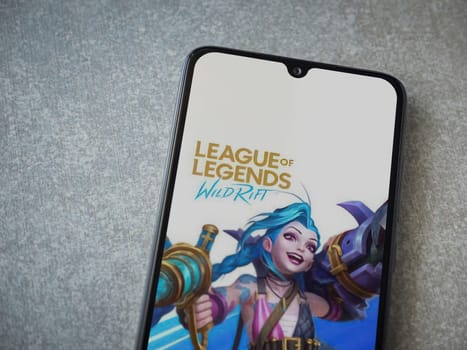 Lod, Israel - July 16,2023: League of Legends - Wild Rift app launch screen on smartphone on ceramic stone background. Top view flat lay with copy space.