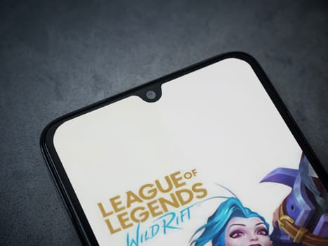 Lod, Israel - July 16,2023: League of Legends - Wild Rift app launch screen on smartphone on dark marble stone background. Top view flat lay with copy space.