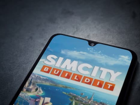 Lod, Israel - July 16,2023: SimCity BuildIt app launch screen on smartphone on dark marble stone background. Top view flat lay with copy space.